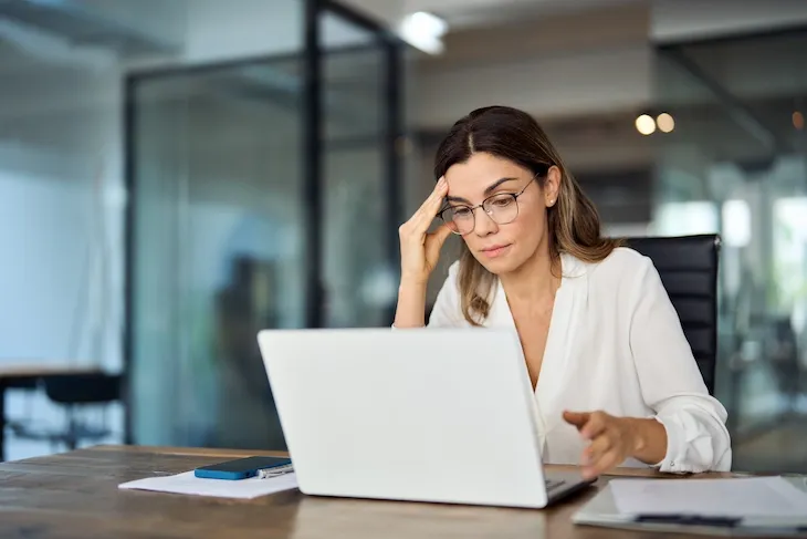 A digital asset manager reviewing files on a laptop in an office.